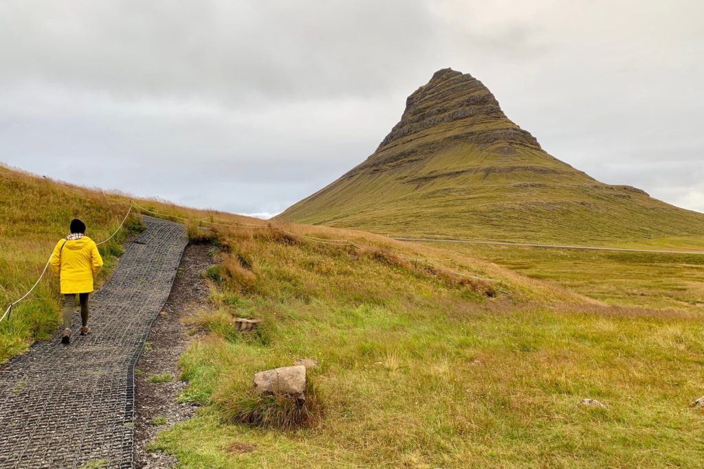 Tamara in yellow raincoat walking towards Kirkjufell mountain