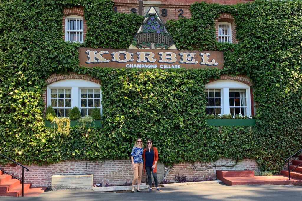 Two women in front of Korbel Champagne Cellars sign