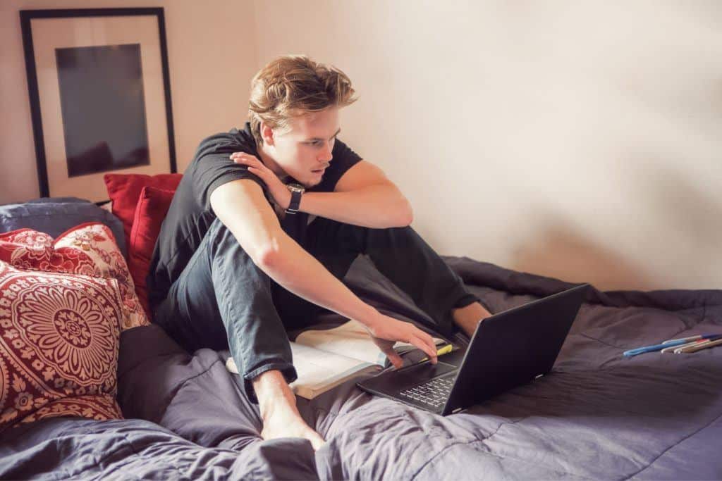 college boy sitting on bed with computer