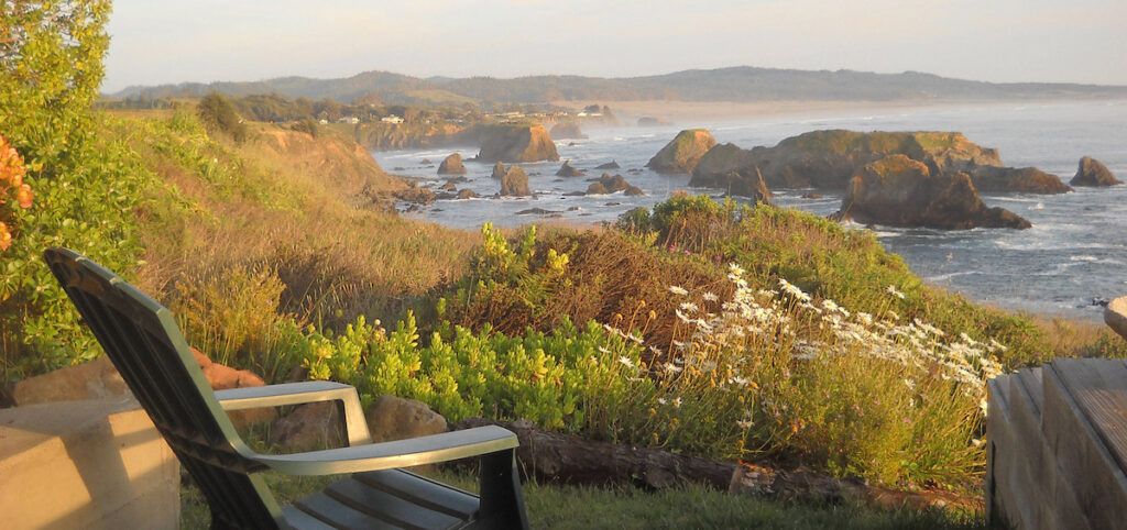 View of rocky coastline from an adirondack chair at the Inn at Newport Ranch