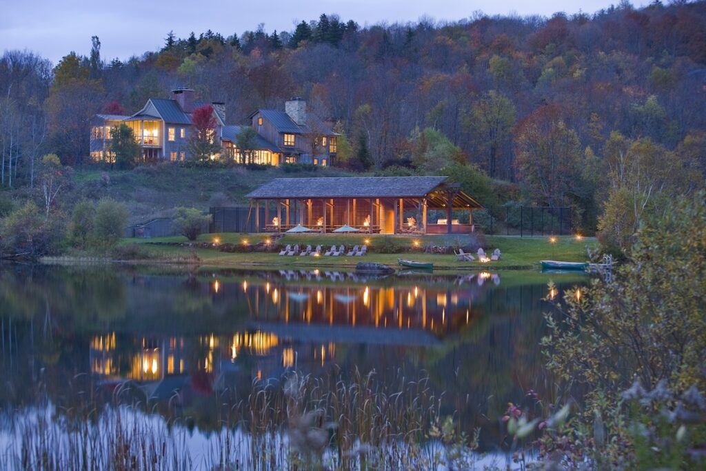 Twin Farms boathouse and lodge in the evening with lights reflecting on the water