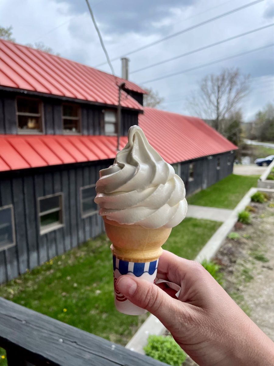 Maple creemee ice cream cone held up in front of a red building