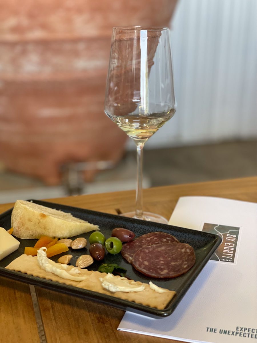 White wine in a glass next to a charcuterie plate