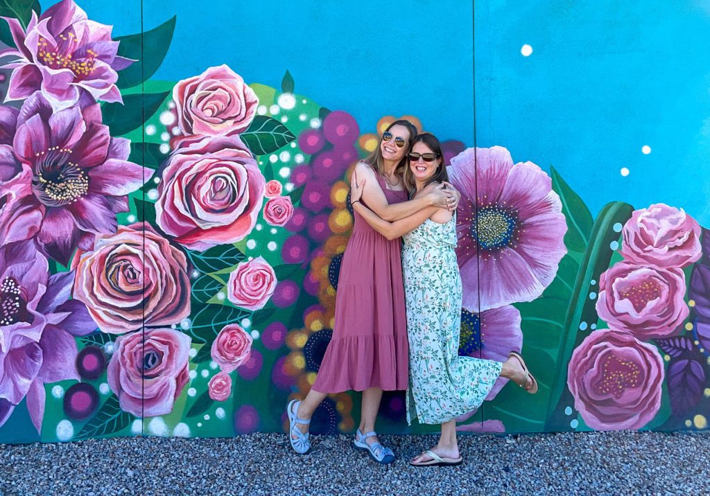 Kim Tate and Tamara Gruber hugging in front of mural in Tempe AZ
