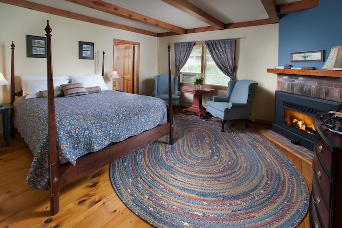 Bedroom with 4 poster bed, braided rug and fireplace at the Snowvillage Inn