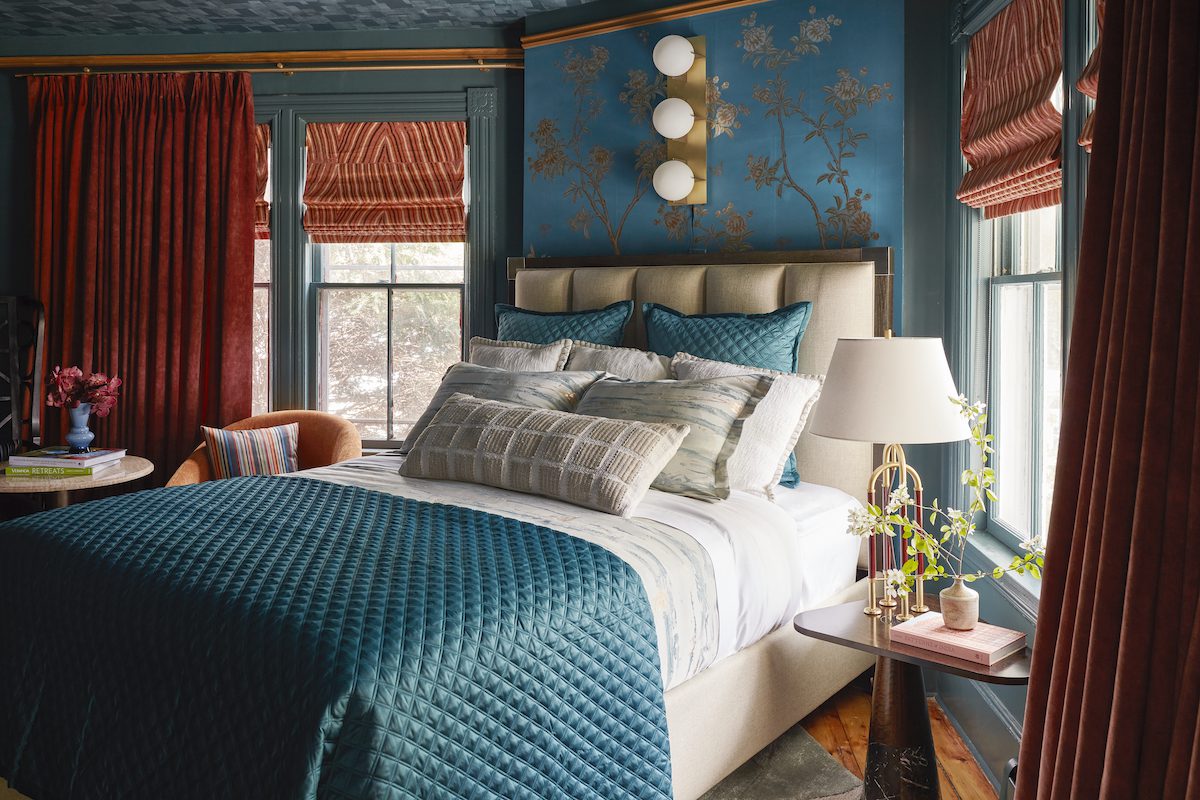Bedroom at the Cornell Inn with blue blanket and walls and red drapes