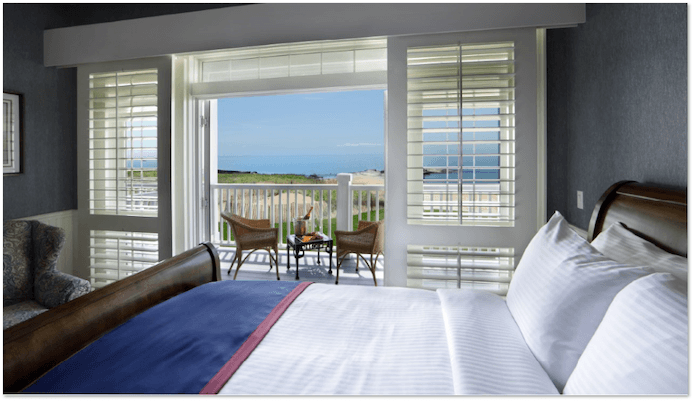 Madison beach hotel guest room with doors open to a balcony with chairs overlooking the beach