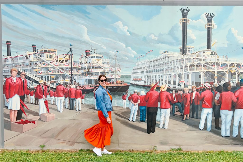 woman in orange dress and jean jacket in front of mural of a steamship in Paducah KY