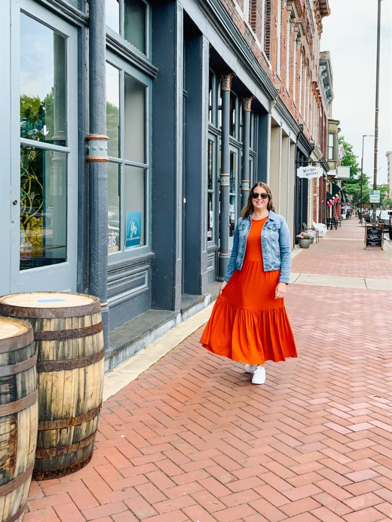 Woman in orange dress and jean jacket strolling down brick street in Paducah, Kentucky
