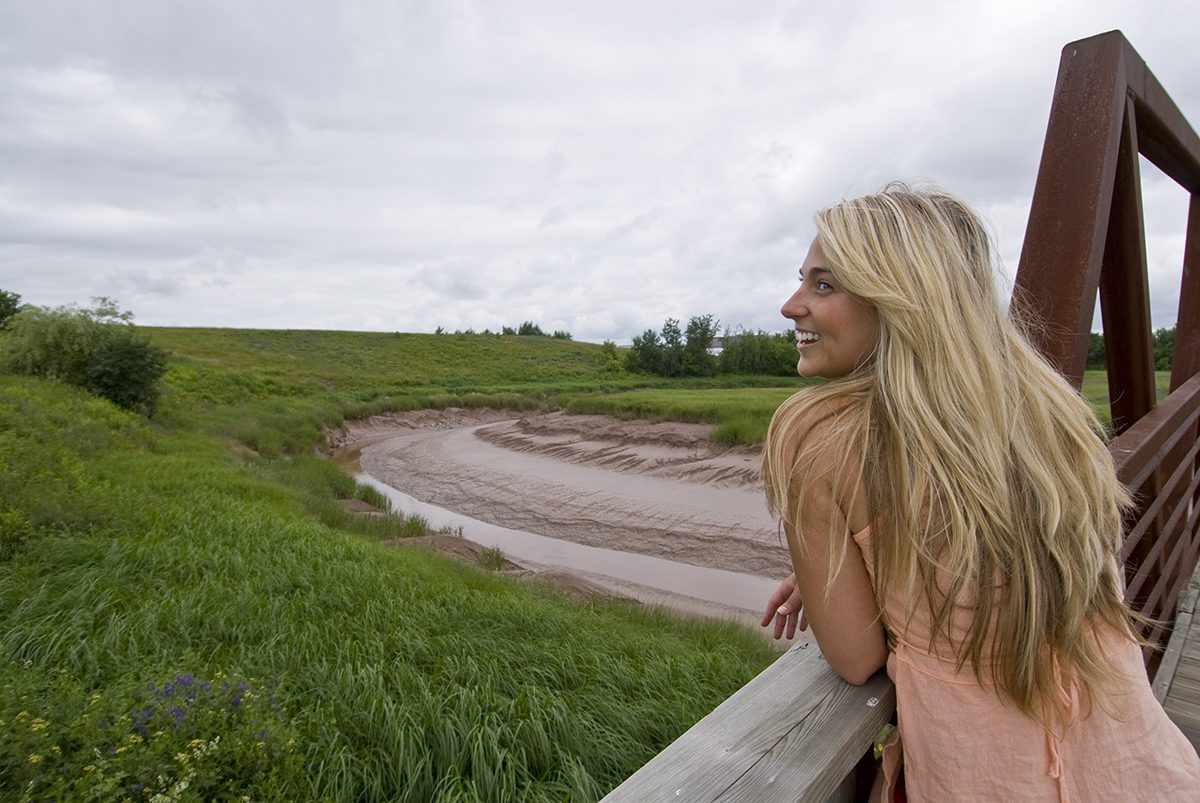 Girl on bridge overlooking Moncton Marsh and river bed