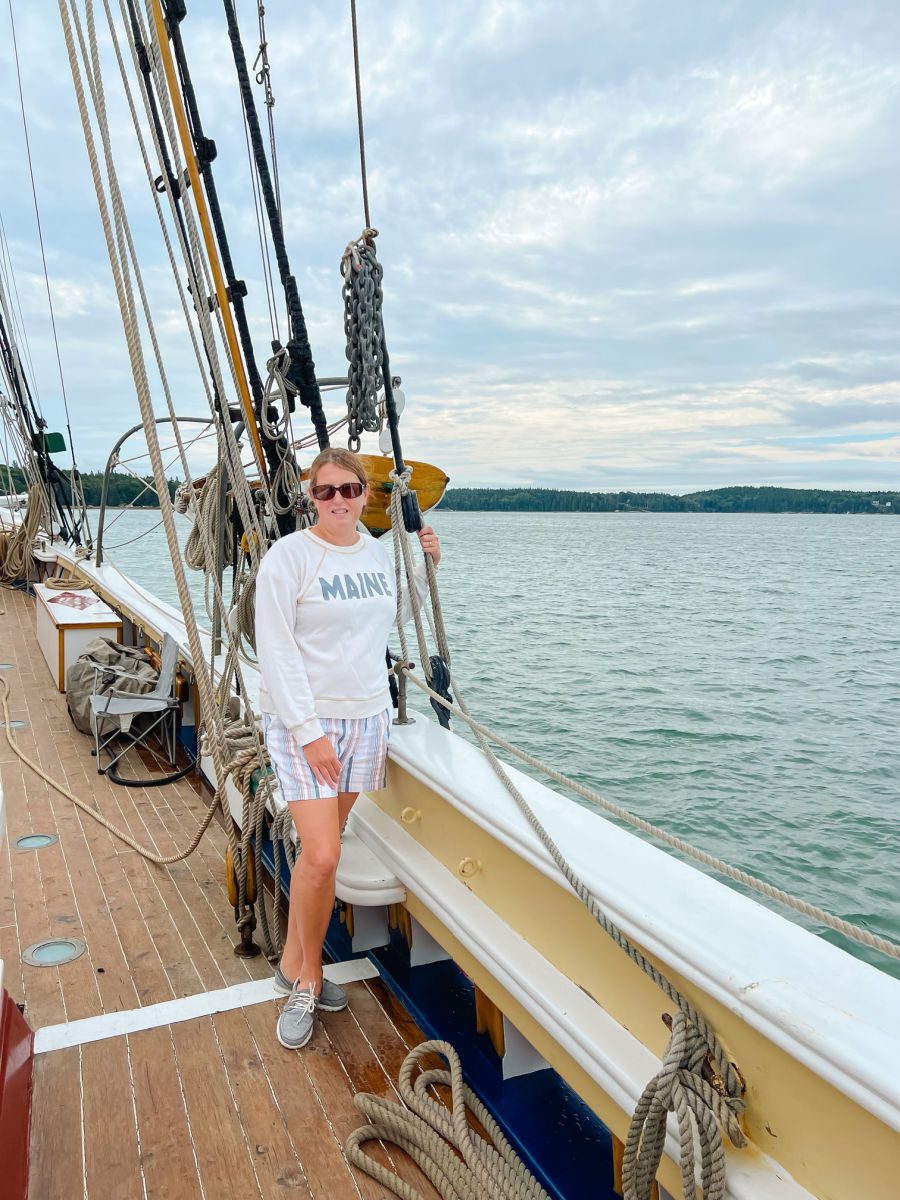 Tamara in Maine sweatshirt and striped shorts on deck of the schooner heritage