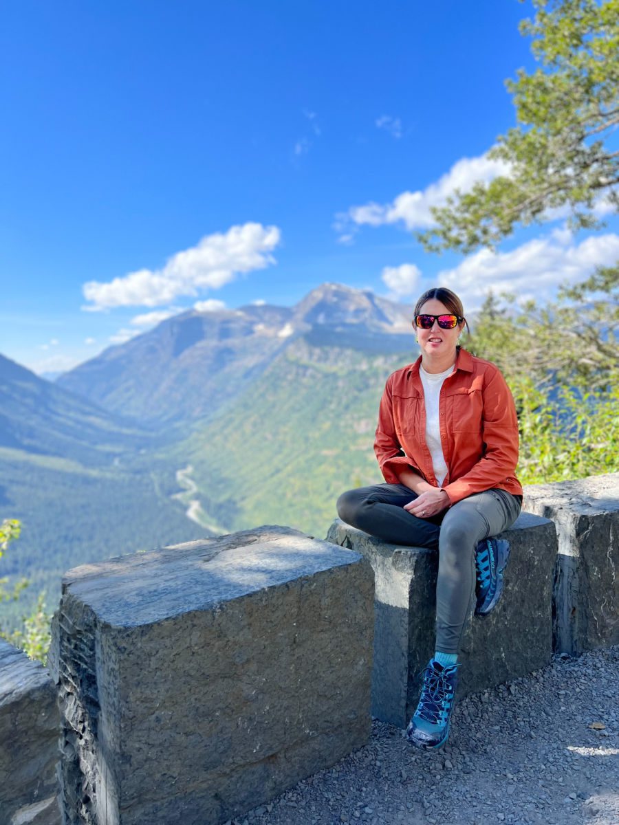 Woman sitting on wall overlooking mountains in Glacier National Park