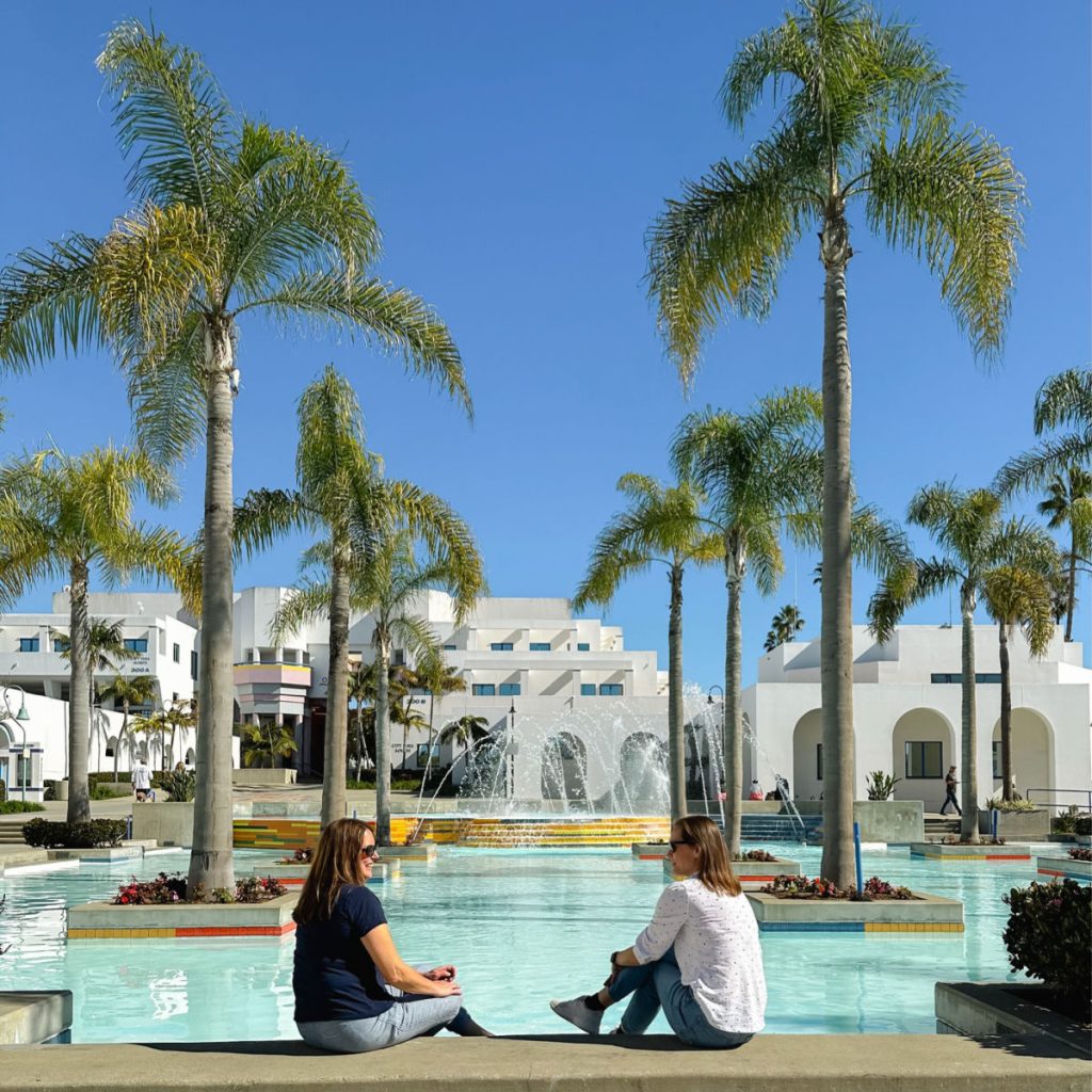 Two women sitting in front of the fountain at the Oceanside Library
