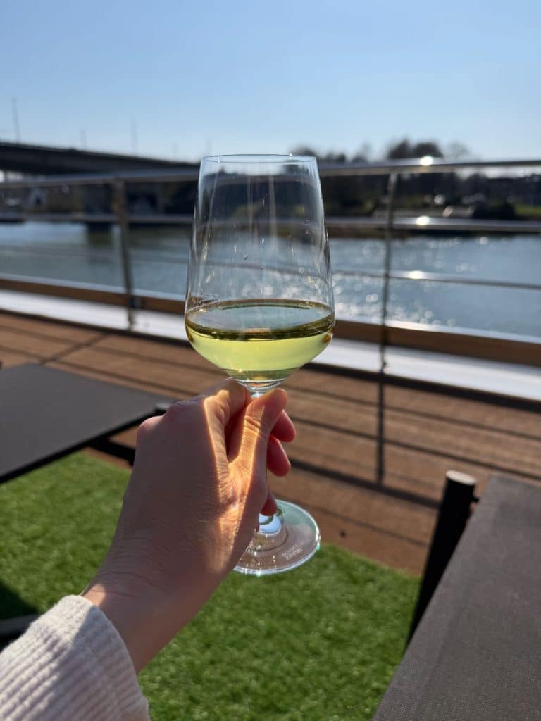 Holding a white wine on the deck of the Scenic Opal river cruise ship